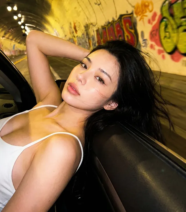 Southeast Asian AI girlfriend leaning out of a car window in a tunnel